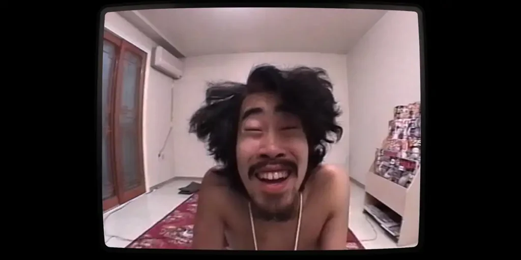 A Japanese man smiles at the camera in the Hulu film The Contestant