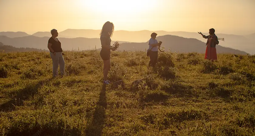 Women stand in a field while picking up grass in a still from the documentary film There Was, There Was Not