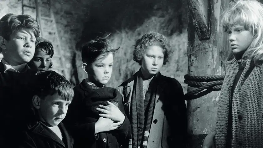 A group of children stand together in a black and white still from Whistle Down the Wind