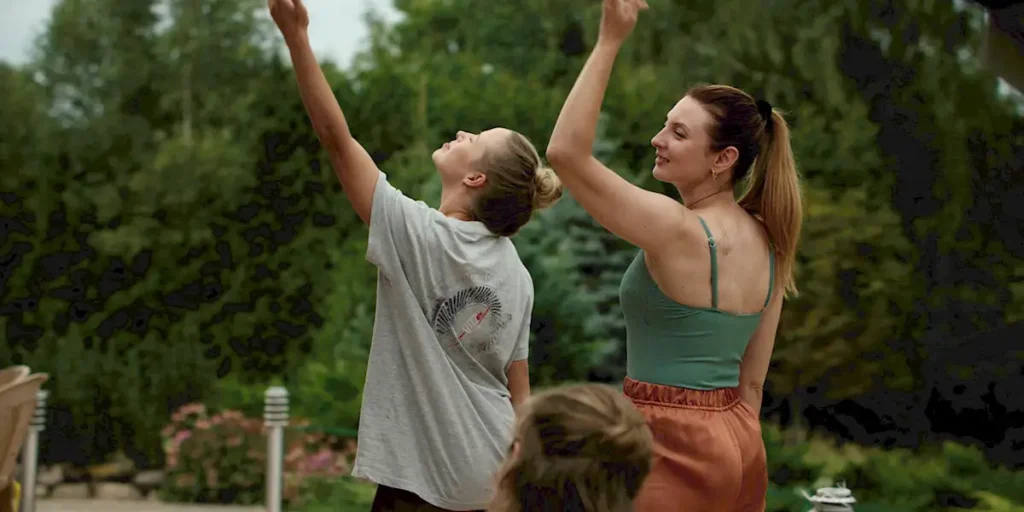 Two women raise an arm looking up at the lake in a still from the film Drowning Dry