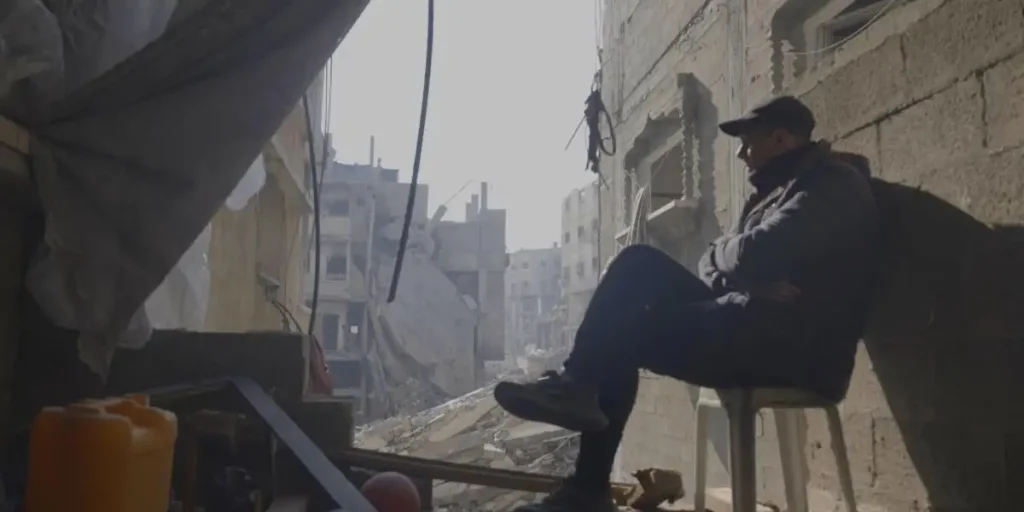 A man leans against a building in a still from the film From Ground Zero