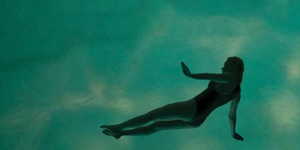 The outline of a woman swimming in a pool seen from below in the film It's Not Me