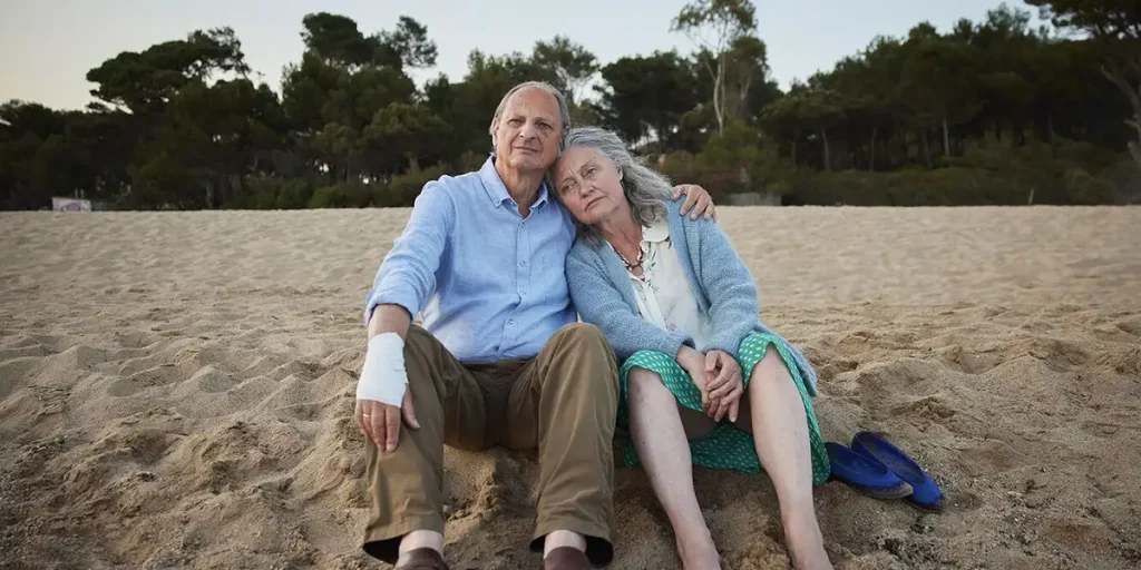 Martin van Waardenberg and Leny Breederveld lean on each other sitting by the beach in Memory Lane