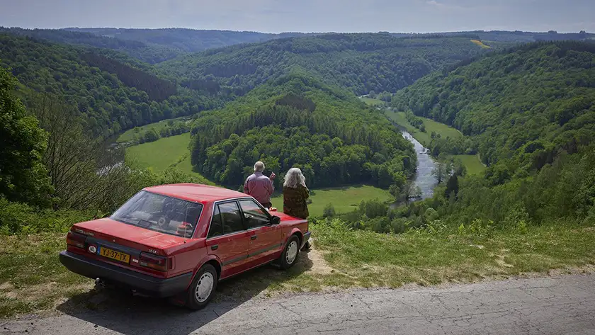 Martin van Waardenberg and Leny Breederveld lean on a red car and look at the valley in Memory Lane