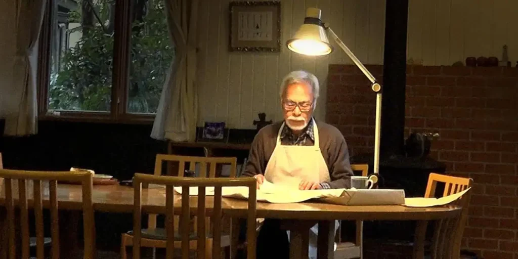 Hayao Miyazaki sit at his desk looking at drawings in Hayao Miyazaki and the Heron