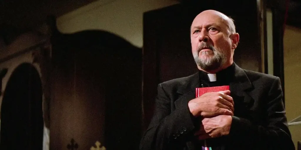 A priest holds the bible close to his chest in John Carpenter's film Prince of Darkness