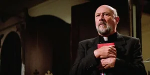 A priest holds the bible close to his chest in John Carpenter's film Prince of Darkness