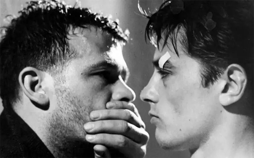 A man has his hand on another man's mouth in the film Rocco and His Brothers