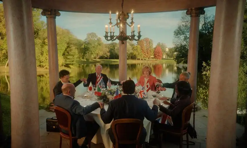 The president, his wife and five more people sit at a round table for lunch with a lake and trees behind them in a still from the film Rumours, one of the 11 Overlooked and Underrated Movies of 2024