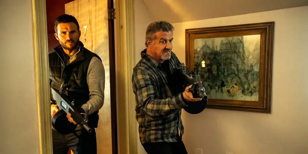 Scott Eastwood and Sylvester Stallone stand by a doorway holding guns in the action crime thriller Alarum