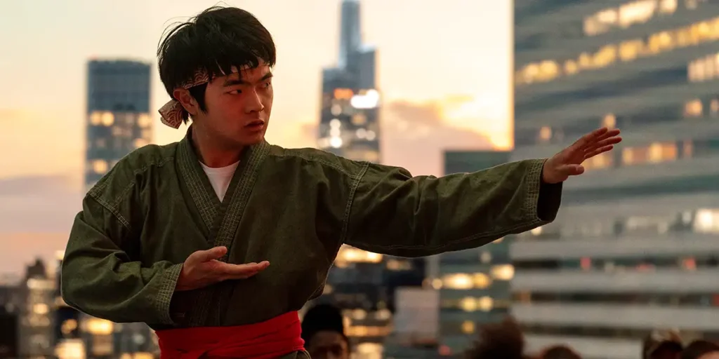 Ben Wang does a martial arts move with his left arm forward in a still from Karate Kid: Legends, featured in an article with everything we know about the movie