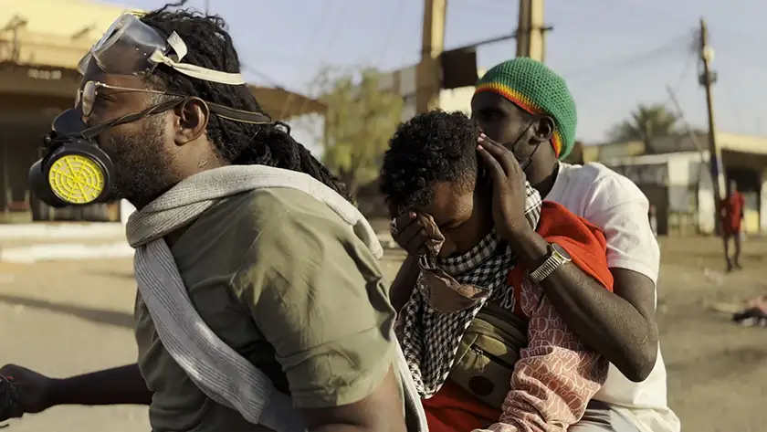 Two men and a boy walk down the street in distress in Sudan in Khartoum by Anas Saeed, Rawia Alhag, Ibrahim Snoopy, Timeea Ahmed and Phil Cox