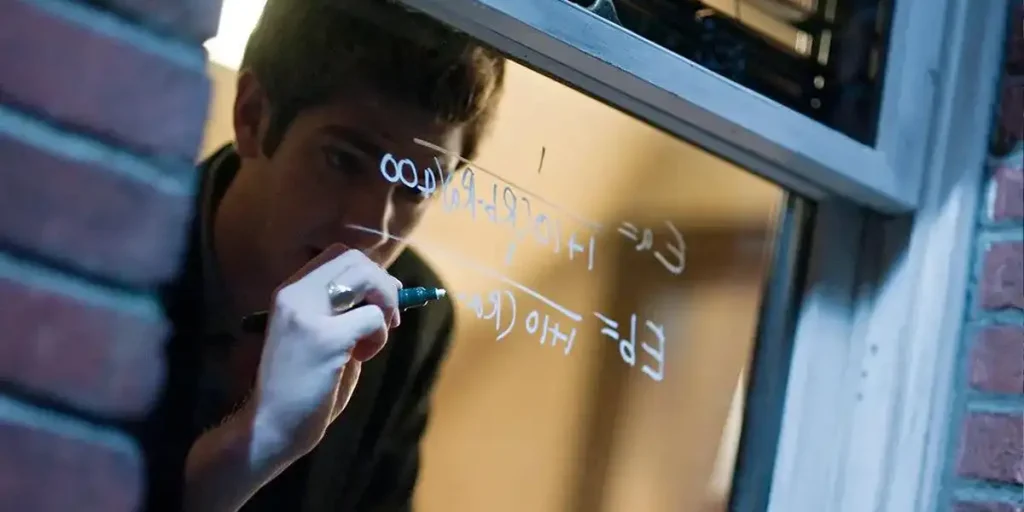 Andrew Garfield writes a line of coding on a window in The Social Network