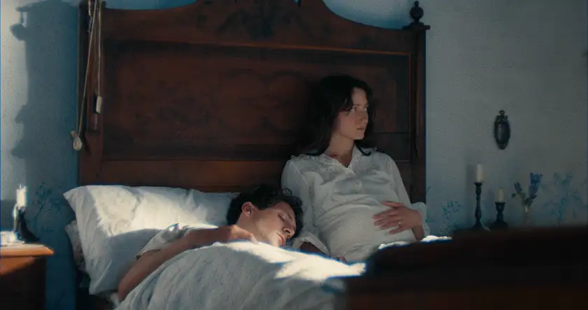 A couple is in bed in the morning in a still from the film Vermiglio, whose director, Maura Delpero, we interview