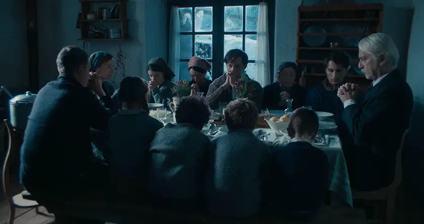 A family sits around the table in a still from the film Vermiglio, whose director, Maura Delpero, we interview