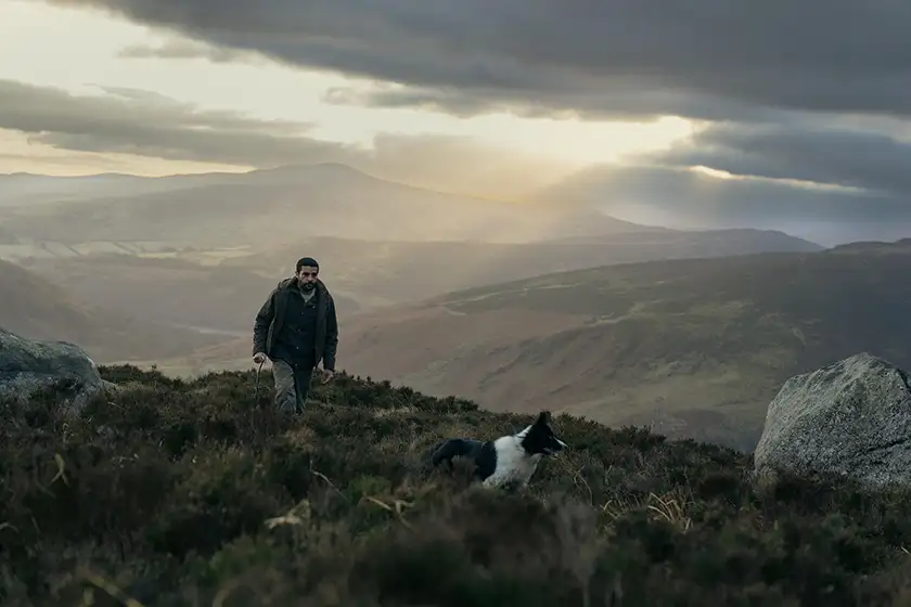 Christopher Abbott follows a Border Collie dog up a hill in Bring Them Down, from director Christopher Andrews whom we interview