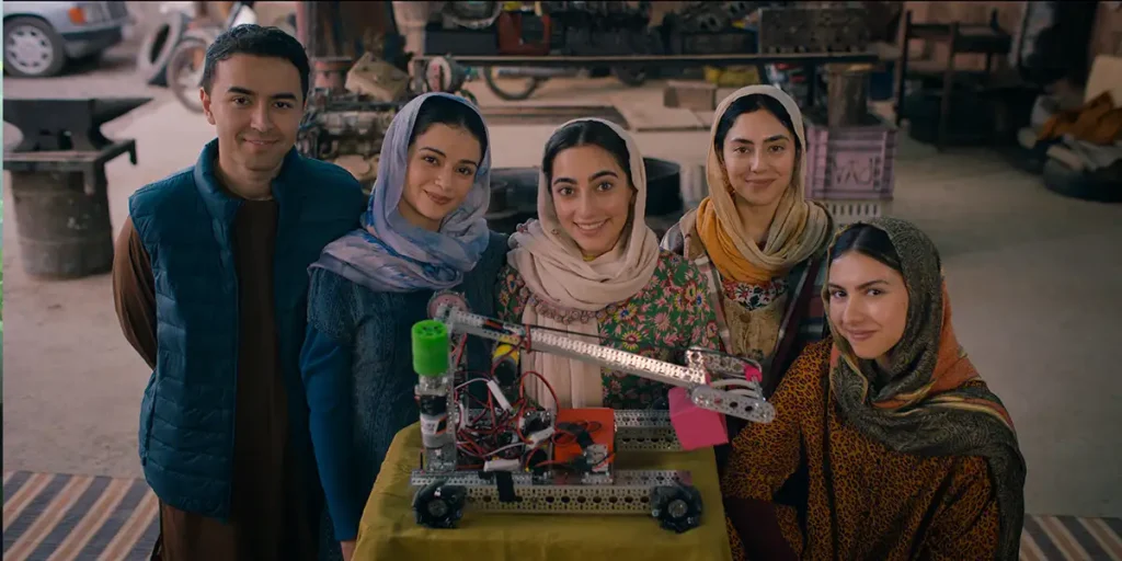 Four Afghan women and a man pose for a picture in a still from Rule Breakers