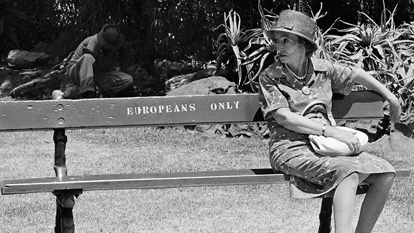 A photo taken by Ernest Cole of a woman sitting on a bench that reads "Europeans Only", featured in the documentary Ernest Cole: Lost and Found