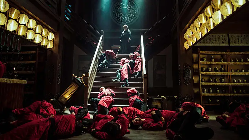 Xie Miao is on top of a staircase with dead bodies all around him in Eye for an Eye 2: Blind Vengeance