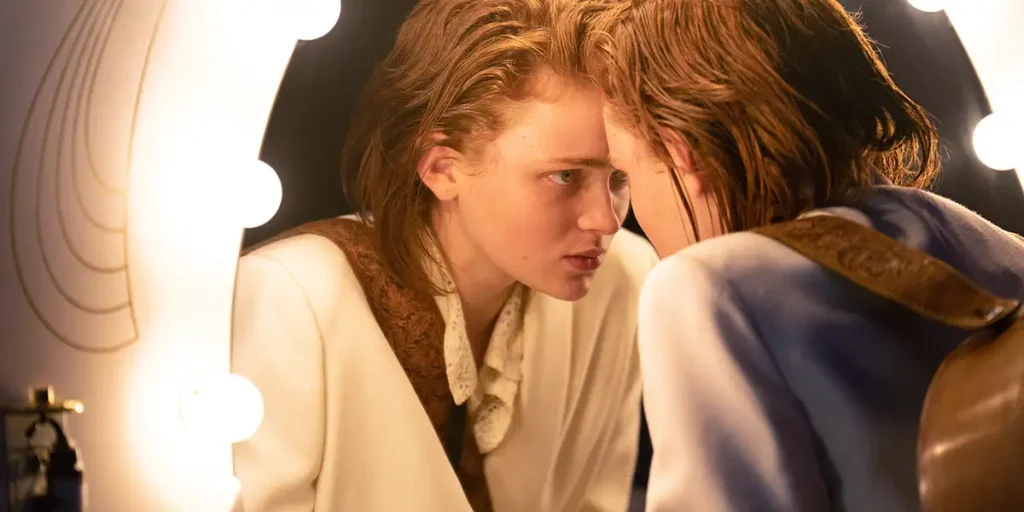 Sadie Sink looks at herself in the mirror in O'DESSA