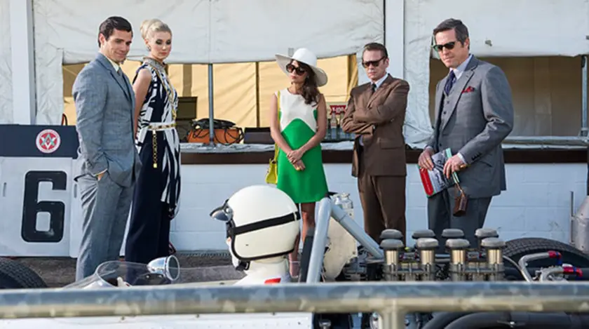 Three men and two women stand looking at a race car in the movie The Man from U.N.C.L.E. 