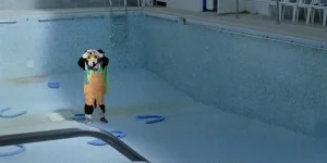 A person wearing a border collie costume stands in an empty swimming pool in a still from The Stimming Pool