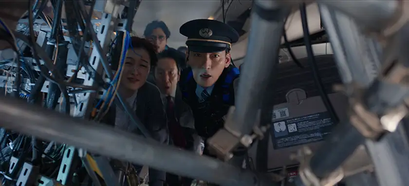 A Shinkansen conductor and three passengers look at a bomb inside the train in fear in a still from the movie Bullet Train Explosion
