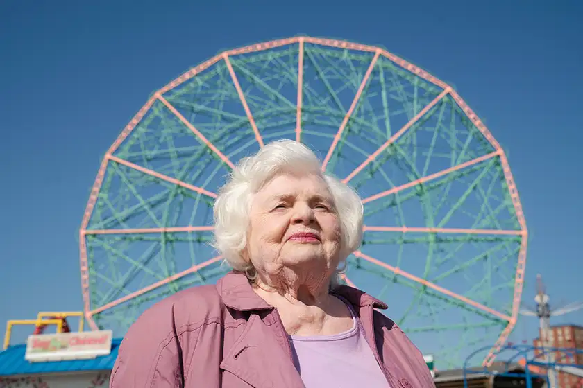 June Squibb stands in front of a ferris wheel in a still from the film Eleanor The Great, one of the 20 movies to watch at the 2025 Cannes film festival according to Loud and Clear Reviews