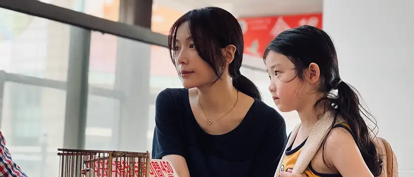 A woman and a girl stand next to each other in a still from the film Left-Handed Girl, one of the 20 movies to watch at the 2025 Cannes film festival according to Loud and Clear Reviews