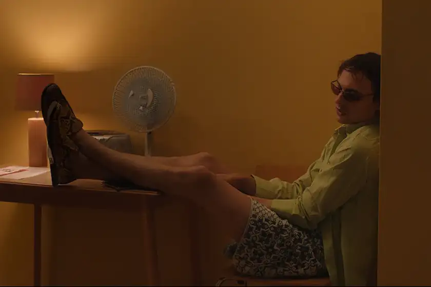 A boy sits with his legs on the table in a still from the film Urchin, one of the 20 movies to watch at the 2025 Cannes film festival according to Loud and Clear Reviews