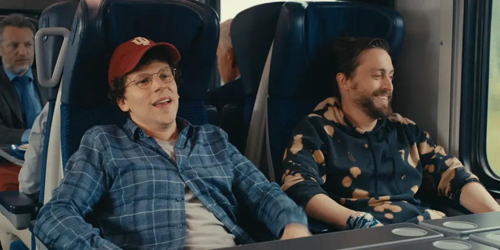 Kieran Culkin and Jesse Eisenberg sit on a train in a still from the film A Real Pain