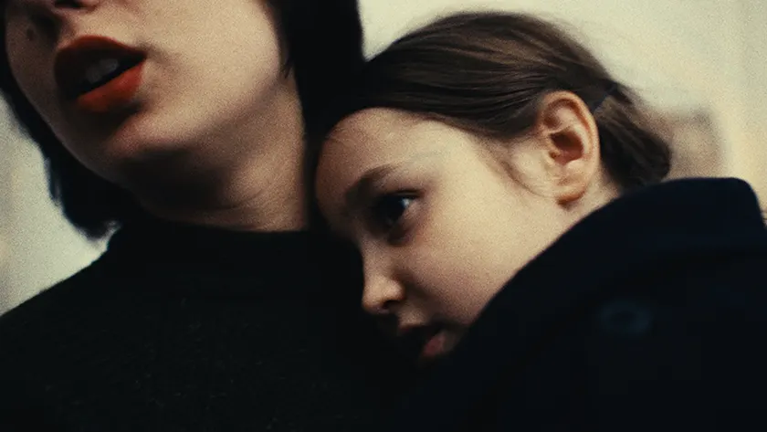 A child leans on her mother in a still from the 2025 film Tell Her I Love Her (Dites-Lui Que Je L'Aime)