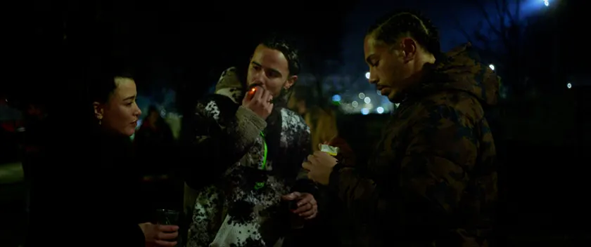 A woman and two men smoke at night in a still from the film Entroncamento (Night Passengers)