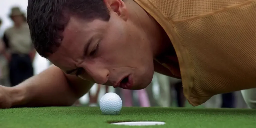 Adam Sandler blows on a hockey ball in Happy Gilmore