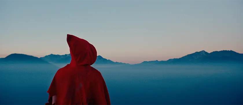 Someone wears a red hood and looks at the mountains in the movie Kryptic