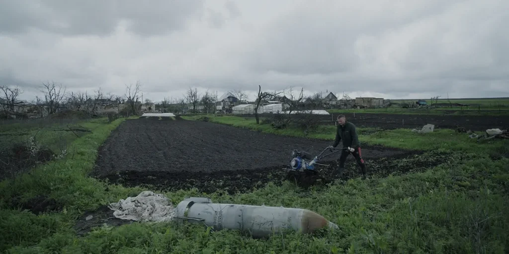 A man works the land in Ukraine next to an unarmed bomb in a still from the documentary film Militantropos