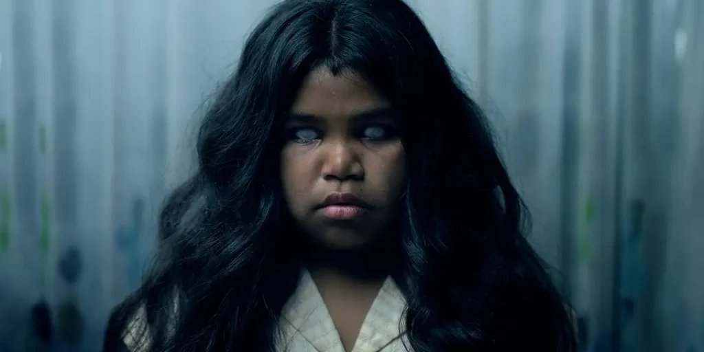 A child with long black hair and white eyes looks possessed in The Moogai
