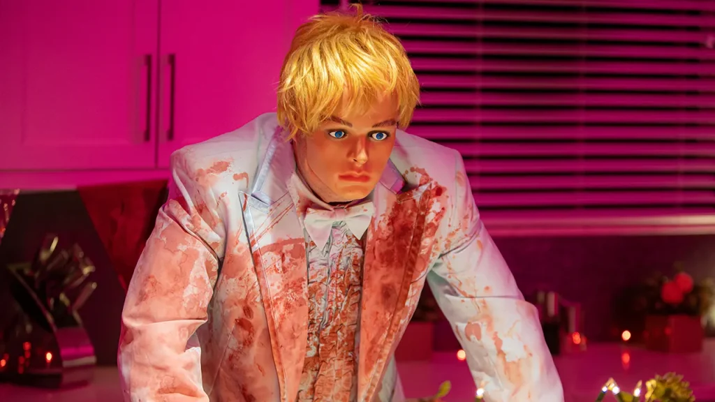A serial killers wears a doll mask and a white suit in the movie Pretty Boy