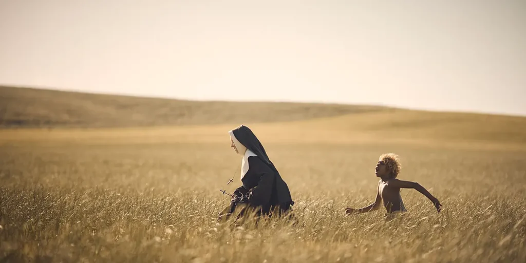 Cate Blanchett as Sister Eileen runs after Aswan Reid as New Boy in a field in a still from the film The New Boy
