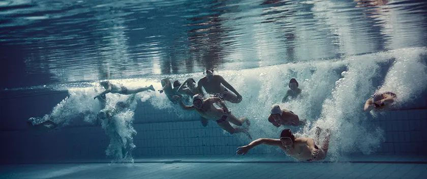 A group of swimmers swim in a swimming pool in an underwater still from Charlie Polinger's 2025 film The Plague