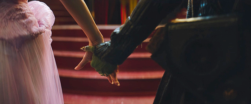 Ariana Grande and Cynthia Erivo hold hands in a still from Wicked: For Good (Part 2), which this article explores what to expect about