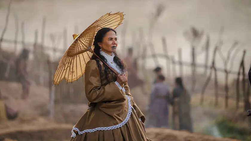 A woman walks with an umbrella in a still from the film In the Fire of War (Ka Whawhai Tonu)