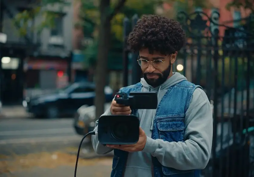 Tristan Turner holds a video camera and films in The Travel Companion