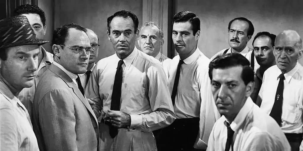 Twelve men stand in a crowded room in a black and white still from the film 12 Angry Men