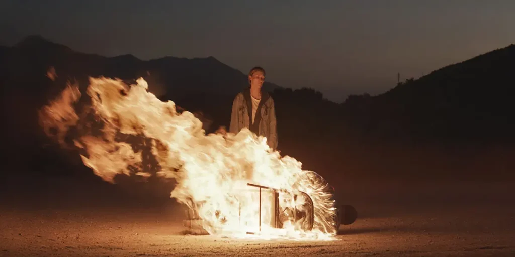A man stands in front of a burning chair in the film Redux Redux