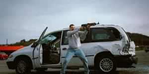 Nick Offerman stands by a car pointing a gun at someone in the 2025 movie Sovereign