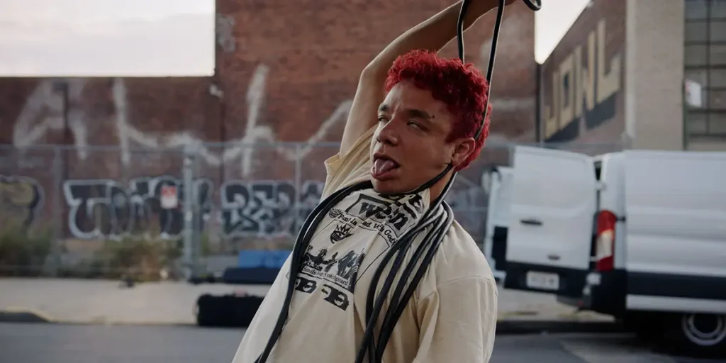 A young man pretends to hang himself with some cables in a still from the film I Fell in Love with a Z-Grade Director in Brooklyn
