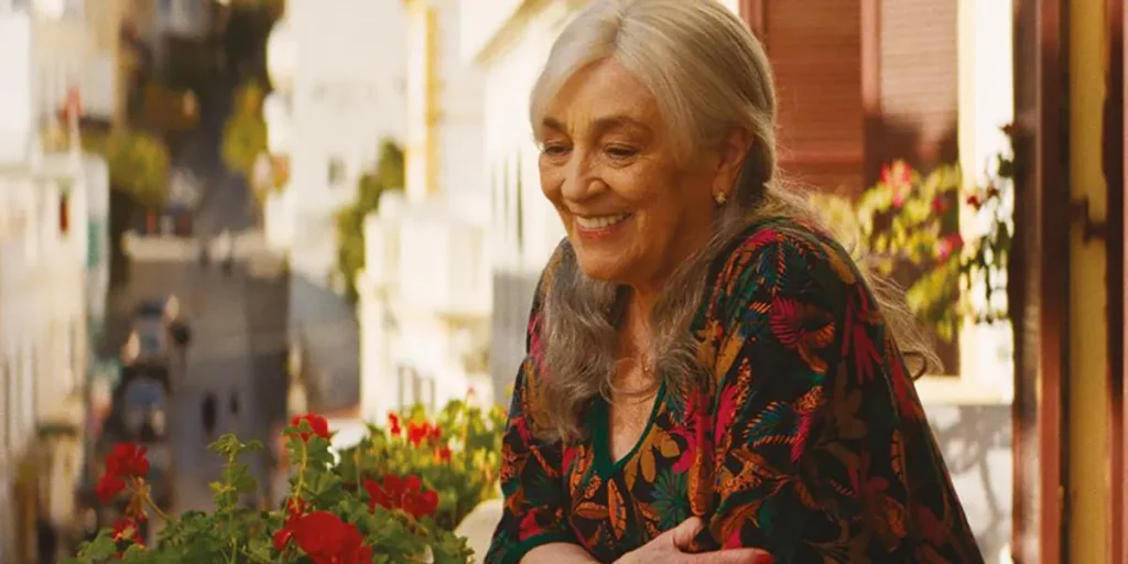 A woman smiles leaning on a table in the movie Calle Malaga