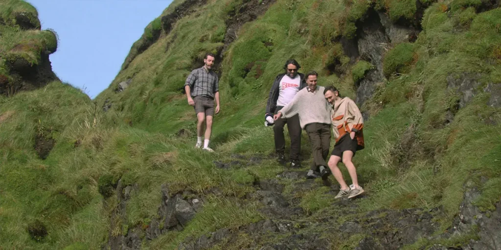 Four people walk down a grassy hill in Celtic Utopia (Útóipe Cheilteach)