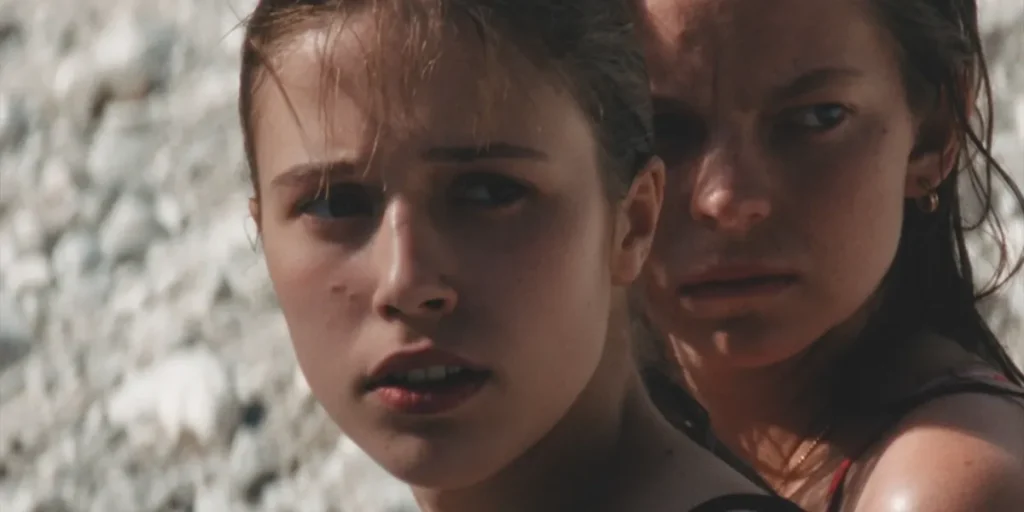 Two girls stand looking to their left in a still from the film Little Trouble Girls (Kaj ti je Deklica)